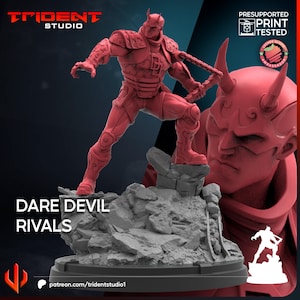 May include: A red 3D-printed figurine of Daredevil in a dynamic pose, holding a weapon, atop a rocky base. The image includes a larger bust of a horned figure and the text "DARE DEVIL RIVALS". The Trident Studio logo is also visible.
