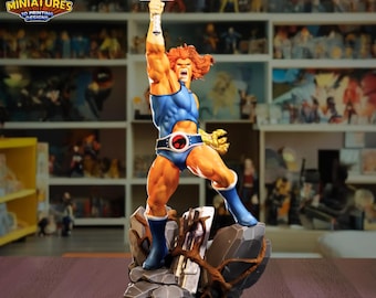 May include: A detailed figurine of a muscular, orange-haired character in a blue bodysuit, raising a sword. The figure stands on a rocky base with a logo that reads "LEGION MINIATURES 3D PRINTING DESIGNS".
