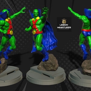 Puede incluir: Un conjunto de tres figuras de Martian Manhunter. Cada figura es verde con un diseño rojo en forma de X en el pecho, capa y botas azules. Las figuras están sobre una base gris. El texto "LEGION MINIATURES" es visible.