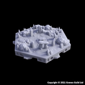 May include: A light gray miniature model of a fantasy landscape, featuring stone structures, trees, and a central circular area. The model has a hexagonal base with cut-out details. The overall design suggests a tabletop game terrain piece.