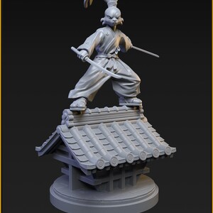 May include: A grey Usagi Yojimbo figurine, a rabbit samurai, stands on a detailed rooftop, holding two swords. The figurine is 40mm tall and is a November Patreon release from C27 Miniatures.