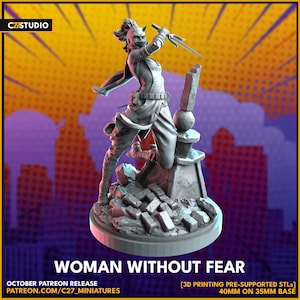以下が含まれることがあります： ダイナミックなポーズで三叉槍を振りかざす女性の灰色の3Dプリントフィギュア。フィギュアは円形の台座にあり、下に「WOMAN WITHOUT FEAR」の文字があります。ベースは35mmベースで40mmです。