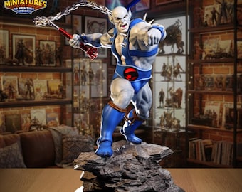May include: A detailed figurine of a muscular, light-skinned character in a blue and white outfit, posed on a rocky base. The figure is holding a weapon and has a determined expression. The "LEGION MINIATURES" logo is visible in the top left corner.