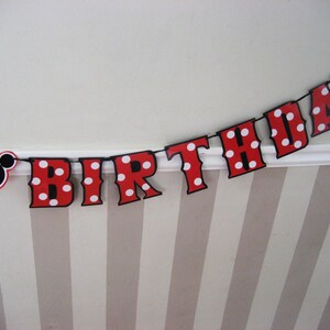 May include: Red and white polka dot birthday banner with black letters spelling out "Birthday" and a black Mickey Mouse head on the left side.