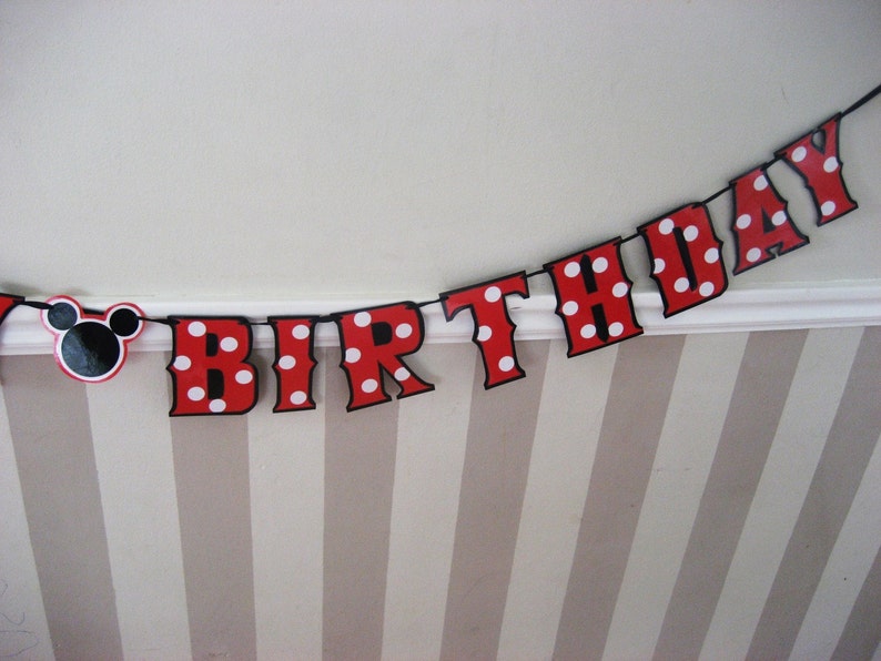 May include: Red and white polka dot birthday banner with black letters spelling out "Birthday" and a black Mickey Mouse head on the left side.
