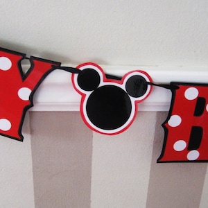 May include: Red and black banner with white polka dots that reads "Happy Birthday". The banner features a Mickey Mouse head in the middle.