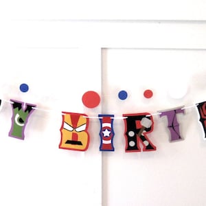 Pu&ograve; includere: Uno striscione colorato "Buon compleanno" con personaggi di supereroi. Le lettere sono decorate con immagini di Iron Man, Hulk, Spiderman, Capitan America e Thor.
