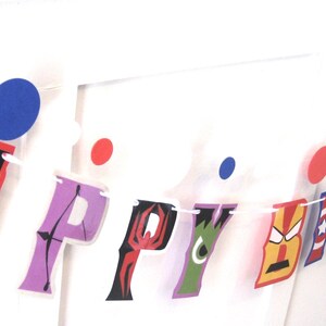 Pu&ograve; includere: Uno striscione di buon compleanno colorato con personaggi di supereroi. Le lettere sono decorate con immagini di Capitan America, Thor, Iron Man, Spider-Man, Hulk e un motivo a pois bianco e nero.