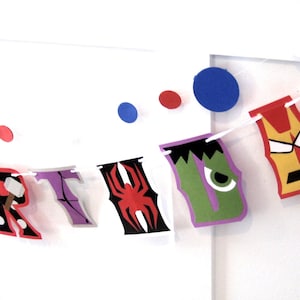 Pu&ograve; includere: Uno striscione di compleanno colorato con personaggi di supereroi. Lo striscione scrive "BIRTHDAY" con ogni lettera rappresentata da un supereroe diverso. I personaggi includono Iron Man, Capitan America, Thor, Hulk e Spiderman.