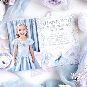 Könnte beinhalten: Hellblaue Dankeskarte mit einem Foto eines lächelnden Kindes in einem blauen Kleid und Diadem. Die Karte trägt die Aufschrift "DANKE FÜR DAS FEIERN MIT MIR!" und enthält den Namen "CLARA". Die Karte ist mit Blumen- und Schneeflockenmotiven verziert.