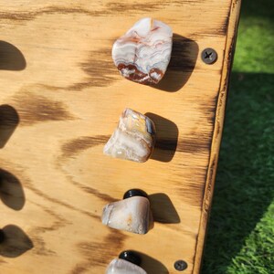 Pu&ograve; includere: Quattro pomelli in pietra di agata montati su una tavola di legno. I pomelli sono di varie tonalit&agrave; di marrone, bianco e grigio con motivi a spirale.