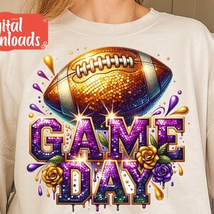 May include: A white sweatshirt with a purple and gold sequined design of a football and the words "GAME DAY".