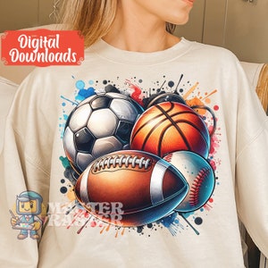 May include: Cream-colored sweatshirt featuring a vibrant graphic of a soccer ball, basketball, football, and baseball with colorful paint splatters. The words "Digital Downloads" are in a red box.