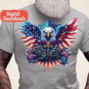 May include: A gray t-shirt with a graphic of an American bald eagle with wings spread, holding a cross. The eagle is superimposed on an American flag. Five police officers are standing in front of the eagle, holding guns. The graphic is surrounded by red, white, and blue watercolor splatters.