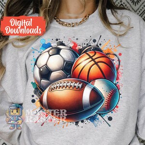 May include: A light gray sweatshirt featuring a colorful graphic of a soccer ball, basketball, football, and baseball. The design includes watercolor paint splatters and the text "Digital Downloads".