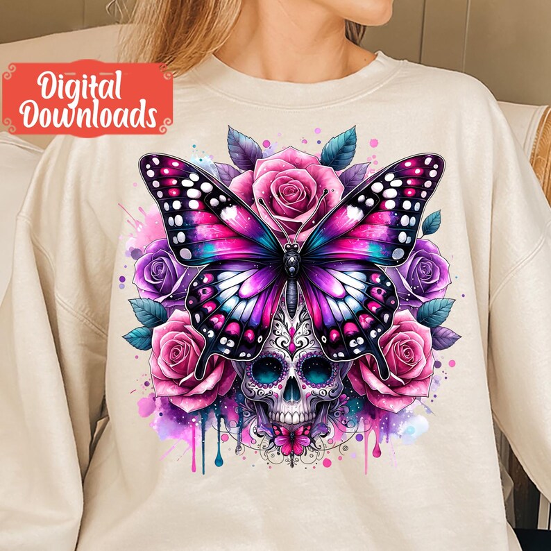 Peut inclure: Un sweat-shirt blanc avec un motif color&eacute; d'un papillon avec un cr&acirc;ne au centre. Le papillon a des ailes roses, violettes et bleues et est entour&eacute; de roses roses.
