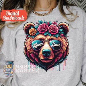May include: A colourful illustration of a bear wearing sunglasses with the words "Mama Bear" on the lenses. The bear is wearing a flower crown with pink, red and yellow flowers.