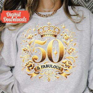 K&ouml;nnte beinhalten: Ein graues Sweatshirt mit einem goldenen Glitzerdesign, das eine Krone und die Zahl 50 zeigt, mit dem Text "& FABULOUS".