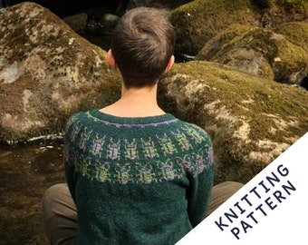 May include: A green knitted sweater with a crew neck and a patterned yoke. The yoke features a repeating design in shades of purple and green. The text "KNITTING PATTERN" is visible in the lower right corner.