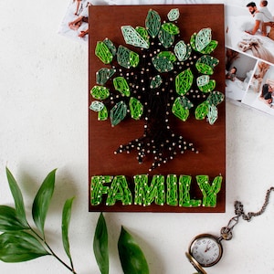 Peut inclure: Une pancarte en bois avec un arbre en fil de fer vert et le mot "FAMILY" écrit en dessous. L'arbre a un tronc et des racines marrons.