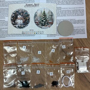 Peut inclure: Un kit de perles pour cr&eacute;er un ornement de No&euml;l. Le kit comprend une vari&eacute;t&eacute; de perles de diff&eacute;rentes couleurs, une aiguille et du fil. Le kit comprend &eacute;galement un motif imprim&eacute; pour l'ornement. L'ornement repr&eacute;sente un bonhomme de neige et un sapin de No&euml;l.
