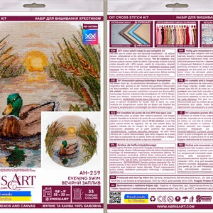 May include: Cross stitch kit featuring a detailed image of a duck swimming in a pond at sunset. The kit includes 35 colors of thread and a Zweigart Aida fabric. The kit is titled "Evening Swim" and is labeled "AH-259".