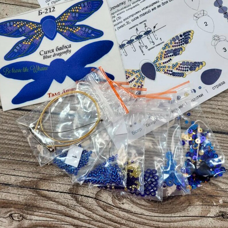 Puede incluir: Un kit de manualidades para hacer una lib&eacute;lula azul con cuentas y lentejuelas. El kit incluye un patr&oacute;n de lib&eacute;lula azul, un aro de alambre y varias bolsas de cuentas y lentejuelas en varios colores, incluyendo azul, dorado y negro. El kit tambi&eacute;n incluye instrucciones para ensamblar la lib&eacute;lula.
