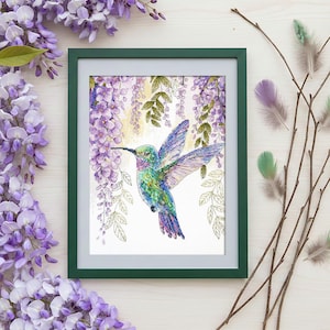 May include: A framed cross-stitch artwork depicting a hummingbird with iridescent blue, green, and purple feathers. The bird is near purple wisteria blossoms. The frame is green, and the background is white.