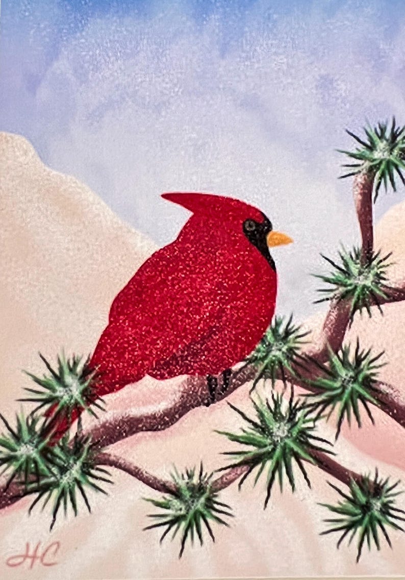 May include: A red cardinal bird perched on a branch of a snow-covered evergreen tree. The background is a soft blue sky with white clouds.