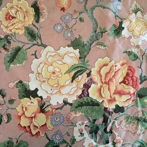May include: A pink fabric with a floral pattern. The fabric features large white, yellow, and pink roses with green leaves. The background is a light pink color.