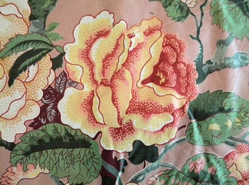 May include: A pink fabric with a floral pattern featuring yellow, red, and green roses. The fabric has a vintage aesthetic.