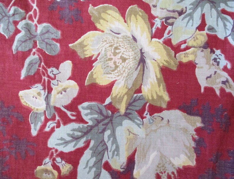 Puede incluir: Una tela roja con un patr&oacute;n floral. Las flores son blancas, amarillas y verdes. La tela tiene un aspecto vintage.