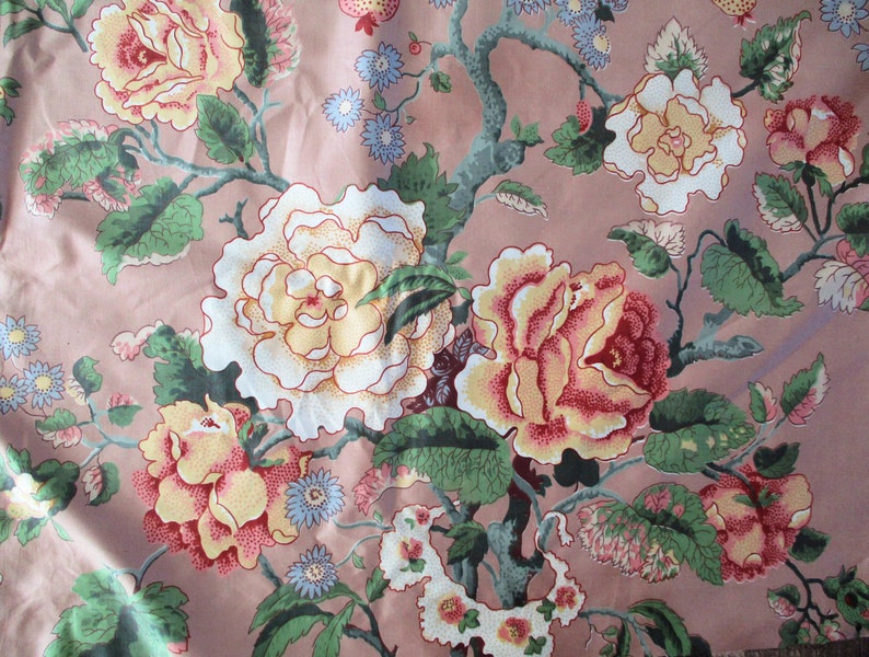 May include: A pink fabric with a floral pattern featuring white, yellow, and red roses with green leaves. The fabric has a vintage aesthetic.
