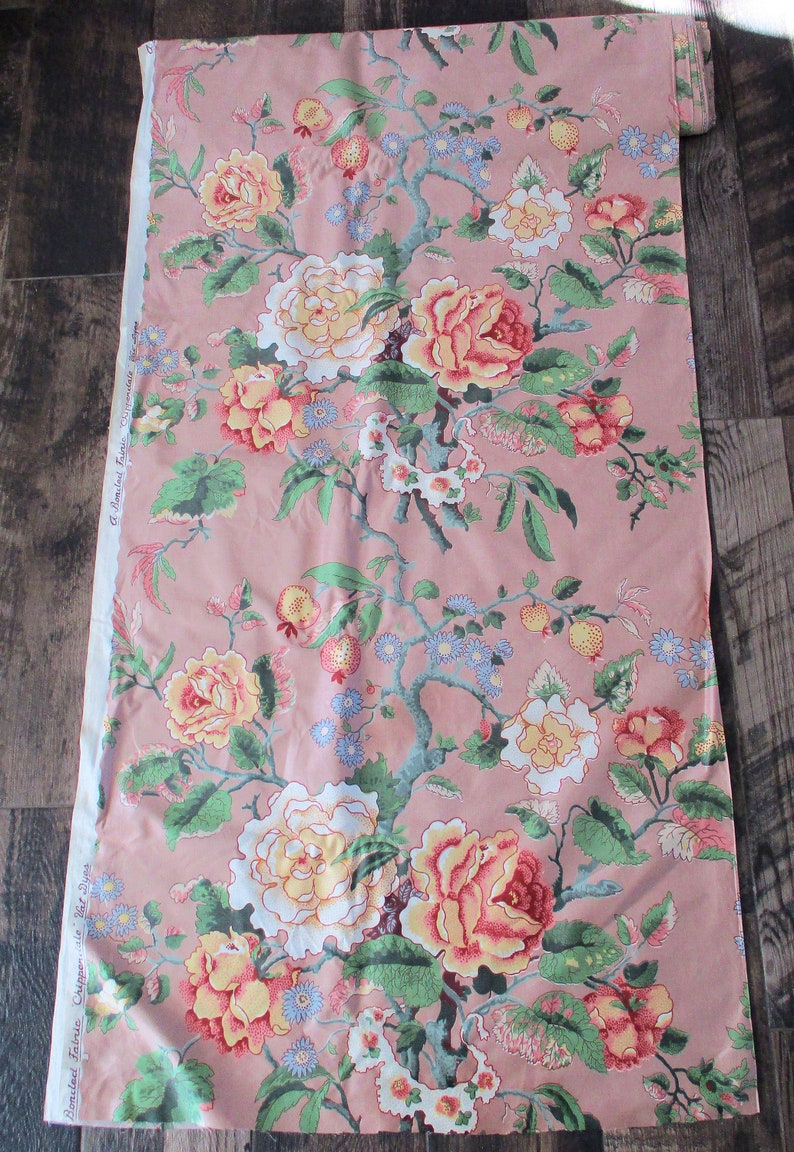 May include: Pink fabric with a floral print featuring large pink, yellow, and white roses with green leaves and small blue flowers. The fabric has the text "Boncland Fabrics, Chicago, Ill." printed on the side.