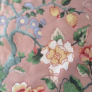 May include: A pink fabric with a floral pattern. The pattern features white, yellow, and red flowers with green leaves. There are also small blue flowers and red berries.