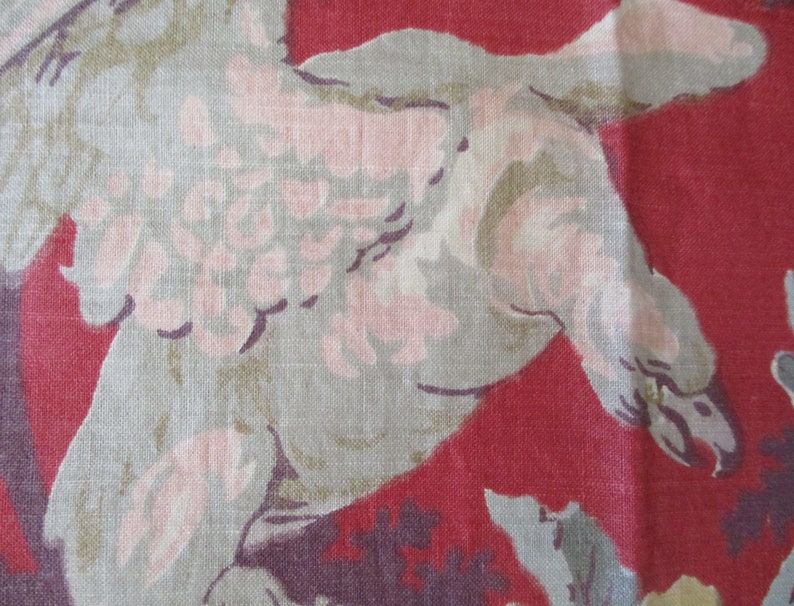 Puede incluir: Primer plano de una tela roja con un dise&ntilde;o de p&aacute;jaro blanco y rosa. El p&aacute;jaro est&aacute; en vuelo y tiene las alas extendidas. La tela tiene una superficie texturizada.