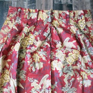 Puede incluir: Tela roja con un patr&oacute;n floral con flores amarillas y p&aacute;jaros blancos. La tela tiene una textura plisada.