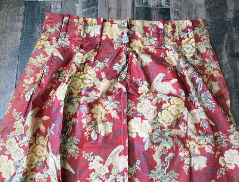 Puede incluir: Tela roja con un patr&oacute;n floral con flores amarillas y p&aacute;jaros blancos. La tela tiene una textura plisada.