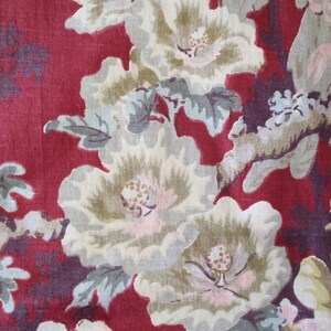 Puede incluir: Tela roja con un patr&oacute;n floral con flores blancas, beige y rosas con hojas verdes. El fondo es de color rojo oscuro.