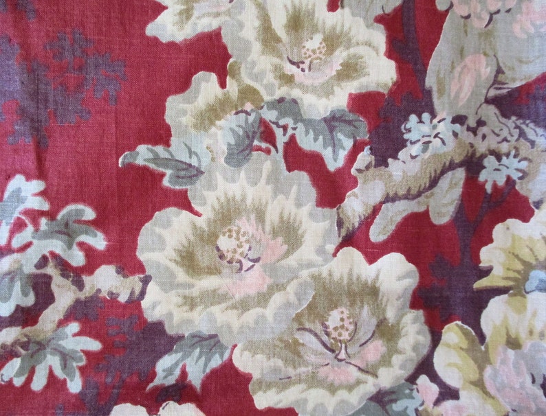 Puede incluir: Tela roja con un patr&oacute;n floral con flores blancas, beige y rosas con hojas verdes. El fondo es de color rojo oscuro.