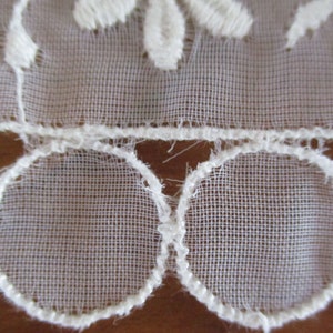 May include: White lace trim with a scalloped edge and a delicate floral pattern.