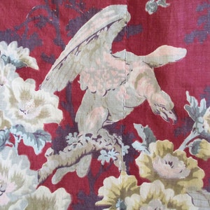 Puede incluir: Tela roja con un p&aacute;jaro blanco y un patr&oacute;n floral. El p&aacute;jaro est&aacute; posado en una rama con las alas extendidas. Las flores son blancas con centros rosados y tienen hojas verdes.