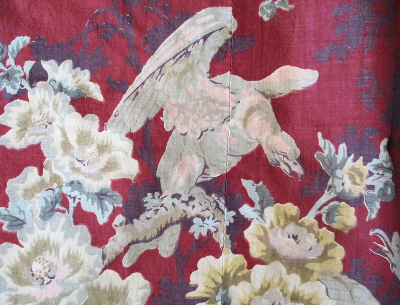 Puede incluir: Tela roja con un p&aacute;jaro blanco y un patr&oacute;n floral. El p&aacute;jaro est&aacute; posado en una rama con las alas extendidas. Las flores son blancas con centros rosados y tienen hojas verdes.