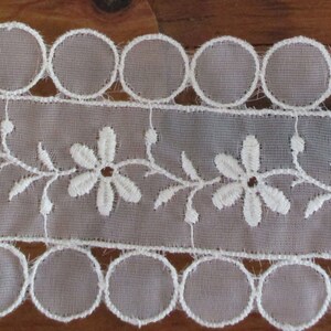 May include: White lace trim with a scalloped edge and a delicate floral design.