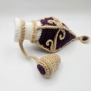 Laying on a flat surface the Royal crochet potion bottle dice bag with the cork to one side.