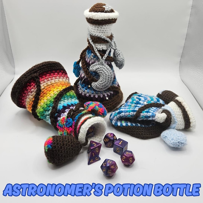 Text reads: Astronomer's Potion Bottle.
Three crocheted potion bottles in different colours. The leftmost has a rainbow gradient, it is lying on its side, with the cork pulled out and coloured polyhedral gaming dice often used in MtG, Magic the Gathering or Warhammer and other boardgames are spilling out of it. A dark blue and purple potion bottle stands tall in the middle with a crescent moon and a star around its neck. A light blue striped potion bottle is squashed / flattened on the right.