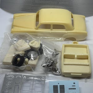 Puede incluir: Un kit de maquetas de coche para construir un coche antiguo. El kit incluye una carrocería de coche de color crema, piezas cromadas y una lámina de piezas metálicas. El kit también incluye una lámina de calcomanías con el logotipo de Mercedes-Benz.