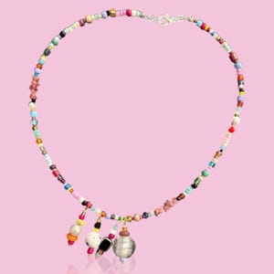 May include: A colourful beaded necklace with multiple charms, including a silver orb, a black and white patterned bead, and a red and orange bead.