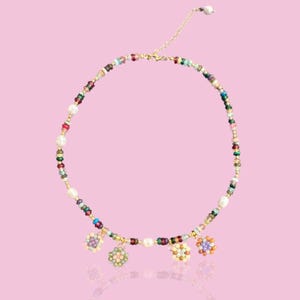 May include: A colourful beaded necklace with a gold chain and three flower-shaped charms. The beads are in shades of red, green, blue, pink, and white.