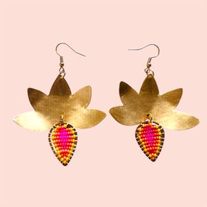 May include: Gold earrings with a lotus flower design and a teardrop-shaped beaded pendant in pink, orange, and yellow.